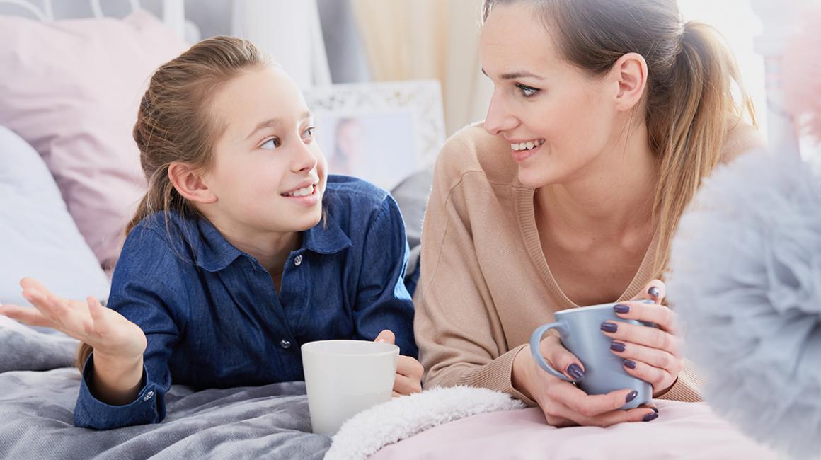 Mama i córka leżą na łóżku z herbatą i rozmawiają