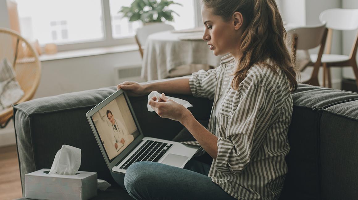 Kobieta z telefonem czeka przed komputerem na e-wizytę