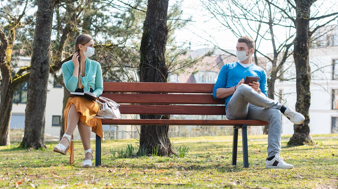 Para w maseczkach na dwóch krańcach ławki