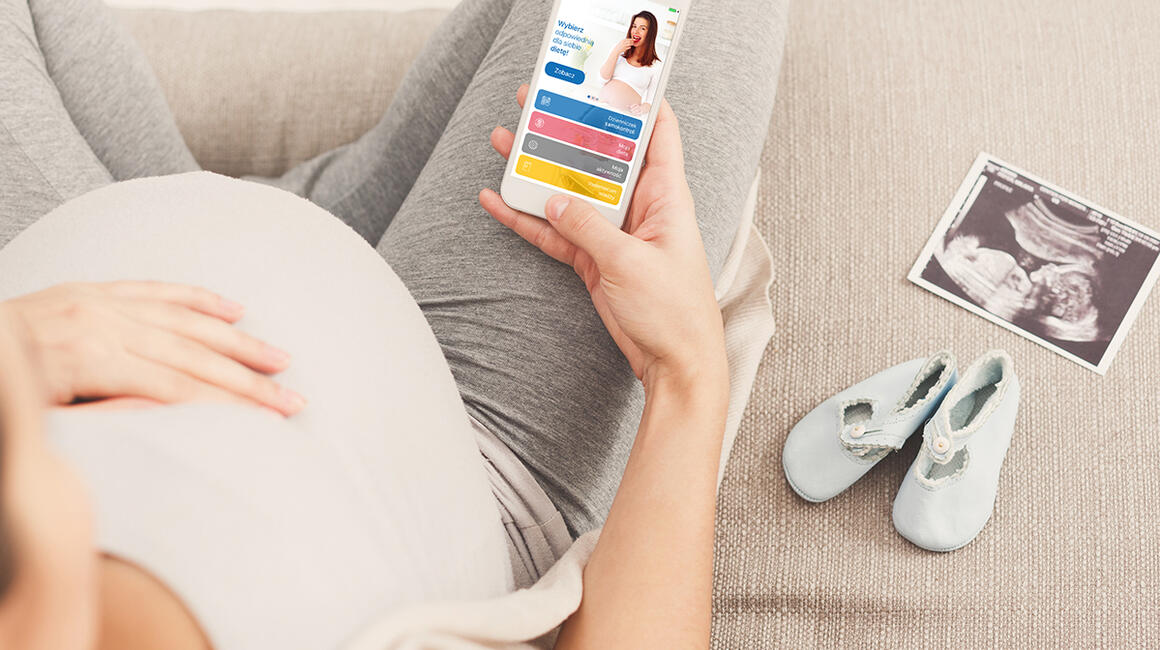 Kobieta w ciąży ogląda aplikację z dietą na komórce