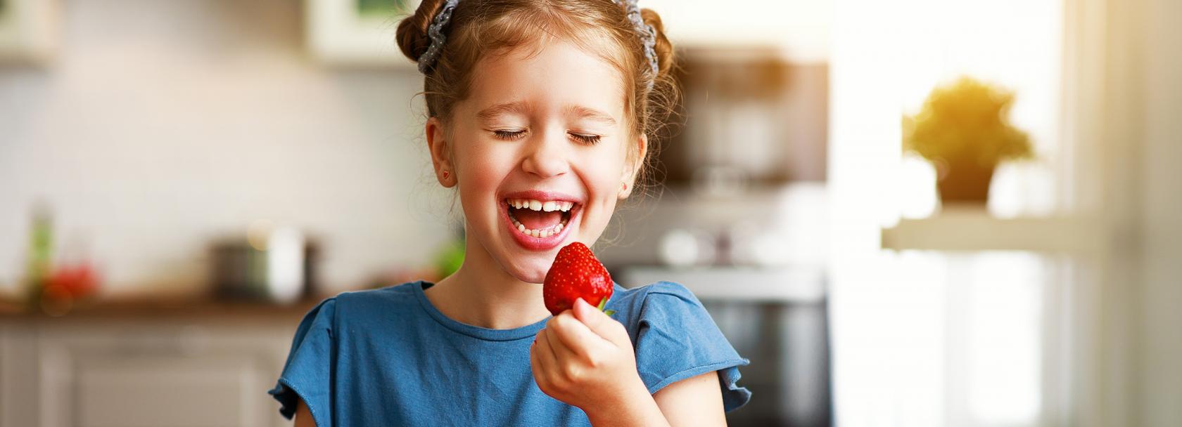 Uśmiechnięta dziewczynka z talerzem truskawek