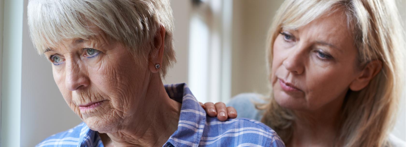 Córka kładzie rękę na ramieniu smutnej matki, starszej pani