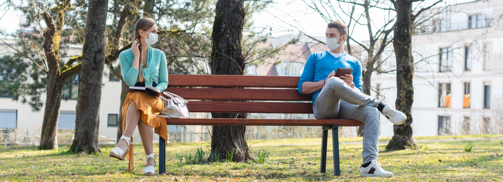 Para w maseczkach na dwóch krańcach ławki