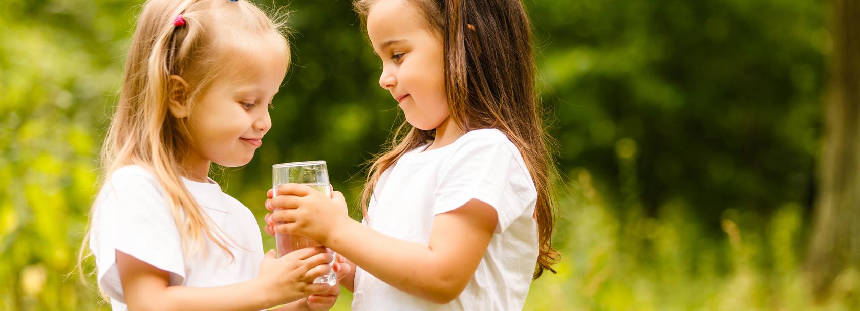 Dziewczynka podaje szklankę wody koleżance