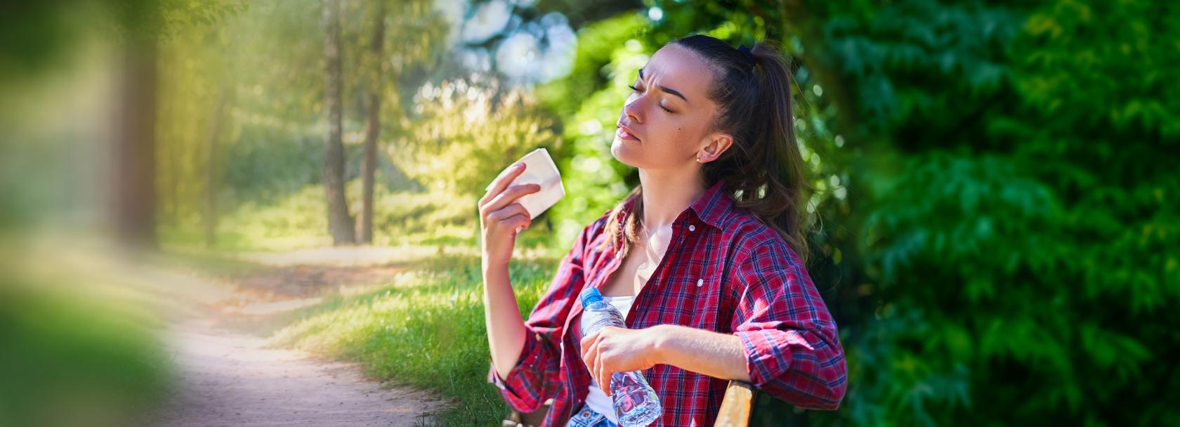 Kobieta wachluje się kartką w parku