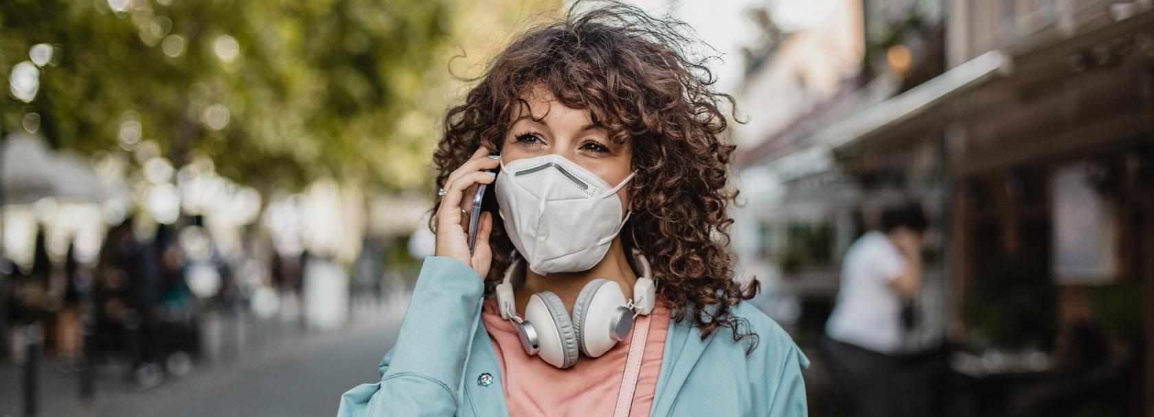 kobieta w maseczce rozmawia przez telefon na ulicy