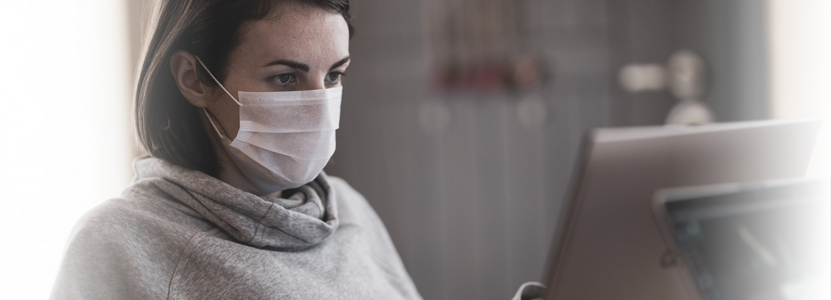 Kobieta w maseczce siedząca przed komputerem.