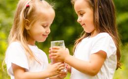 Dziewczynka podaje szklankę wody koleżance