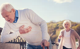 starszy pan trzyma się za serce, żona biegnie na ratunek