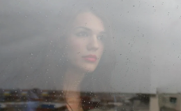 Twarz kobiety stojącej za zamgloną szybą.